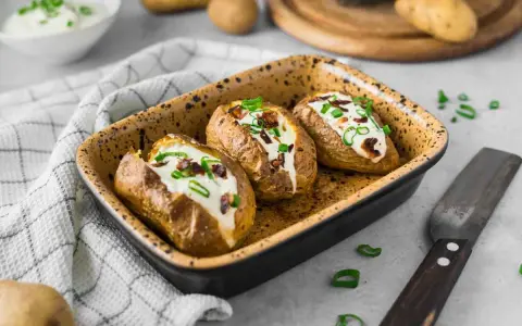 Drei gebackene Ofenkartoffeln mit Sour Cream und Speckwürfeln, ein köstliches Ofenkartoffeln Rezept.