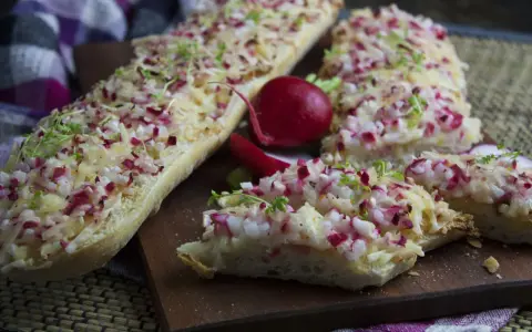 Baguette-Scheiben mit Radieschen und Käse belegt, eine köstliche Idee für Radieschen Rezepte. Frische Kresse garniert die Snacks.