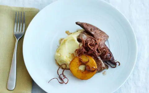 Kalbsleber rezept: Gebratene Kalbsleber mit Kartoffelpüree, Apfelring und knusprigen Zwiebeln auf einem weißen Teller.