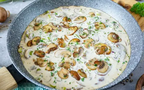 Cremige Rahmchampignons in einer Pfanne, perfekt für ein schnelles und leckeres Rahmchampignons Rezept. Mit frischer Petersilie garniert.