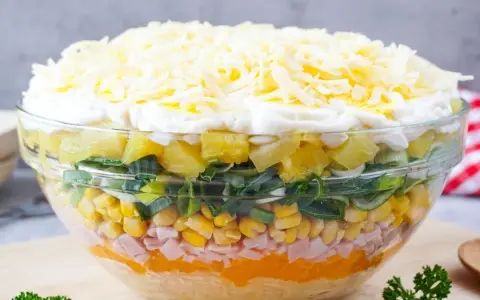 Schichtsalat rezept: Ein bunter Schichtsalat in einer Glasschüssel mit Ananas, Lauch, Mais, Schinken, Orange, Ei und Käse.