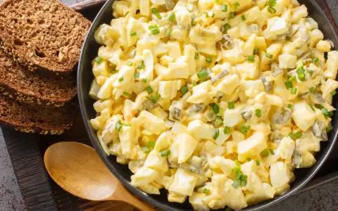 Cremiger Eiersalat mit Gurkenstückchen und Schnittlauch, perfekt für ein einfaches eiersalat rezept. Dazu passen rustikale Brotscheiben.