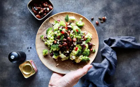 Frischer Brokkoli Salat mit Nüssen und roten Zwiebeln auf einem Holzteller, bereit zum Genießen.