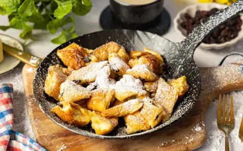 Ein fluffiger Kaiserschmarrn im Pfännchen, bestäubt mit Puderzucker. Perfekt für ein süßes Frühstück oder Dessert.