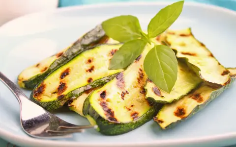 Gegrillte Zucchinischeiben mit Grillstreifen, garniert mit frischem Basilikum. Perfekt für die Sommerküche, diese Zucchini grillen marinade ist ein Genuss.