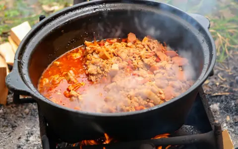Ein dampfender Kessel mit herzhaftem Kesselgulasch, zubereitet über offenem Feuer. Das perfekte Rezept für ein rustikales Outdoor-Erlebnis.