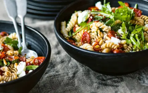 Leckerer Nudelsalat mit getrockneten Tomaten, Pinienkernen und Rucola. Ein einfaches nudelsalat rezept für den Sommer.