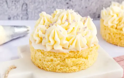 Ein kleiner Kuchen mit omas buttercreme ohne pudding, verziert mit lila Zuckerstreuseln.
