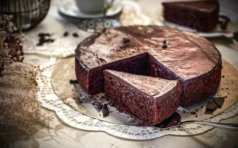 Ein saftiger Schokoladenkuchen mit glänzender Glasur, ein Stück wurde herausgeschnitten. Der einfache Kuchenteig sieht köstlich aus.
