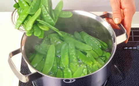 Frische Zuckerschoten werden in einem Topf mit kochendem Wasser zubereitet. Ein einfaches Zuckerschoten Rezept für gesunde Beilagen.