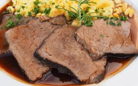 Saftige Scheiben Sauerbraten mit Spätzle und einer Kräutergarnitur. Ein klassisches Sauerbraten Rezept, das Appetit macht.