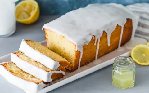 Saftiger Zitronenkuchen mit Zuckerguss, perfekt für ein einfaches zitronenkuchen rezept. Serviert mit frischen Zitronenscheiben.
