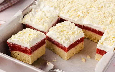 Schichtkuchen mit roter Fruchtschicht, weißer Creme und Schokostreuseln – perfekt als Kuchen zum Muttertag.