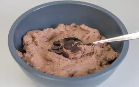 Schokosahne rezept: cremige Schokoladencreme in einer Schüssel, garniert mit Schokodrops und einem Löffel.