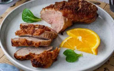 Saftige entenbrust im airfryer, perfekt gebräunt und in Scheiben geschnitten, serviert mit frischen Orangenscheiben und grünen Blättern.