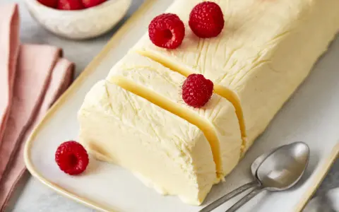 Cremiger Rhabarber Pudding, dekoriert mit frischen Himbeeren, auf einem Teller mit Löffeln.