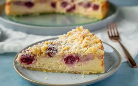 Ein Stück saftiger, schneller Quark Kirsch-Kuchen mit Streuseln und Puderzucker bestäubt.