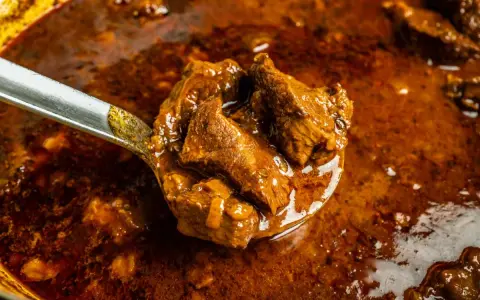 Ein Löffel voller herzhaftem Wildschweingulasch, bereit zum Servieren. Dieses Wildschweingulasch Rezept verspricht ein köstliches Gericht.