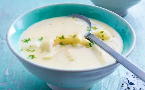 Cremige Spargelsuppe mit Petersilie in einer blauen Schüssel. Perfekt zum Spargelsuppe einfrieren für später.