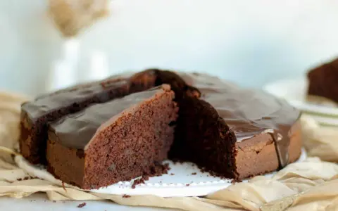 Ein saftiger Schokokuchen mit glänzender Glasur, perfekt für jedes schokokuchen rezept. Ein Stück ist bereits angeschnitten.