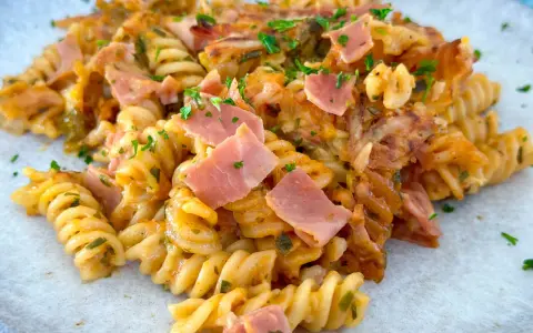 Nudel Schinken Gratin mit Käse überbacken, garniert mit Petersilie. Ein herzhaftes Gericht, das zum Genießen einlädt.