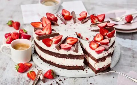 Eine köstliche Yogurette Torte mit frischen Erdbeeren und Schokostückchen, serviert mit einer Tasse Kaffee.