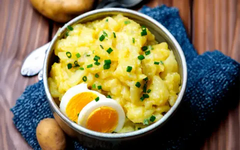 Omas Kartoffelsalat, cremig und mit Schnittlauch bestreut, serviert mit gekochten Eiern. Ein Klassiker, der immer schmeckt.