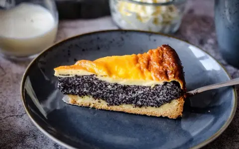 Ein saftiges Stück Mohnkuchen mit Pudding-Schicht auf einem blauen Teller, bereit zum Genuss.