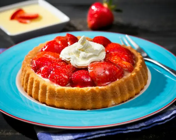 Erdbeerkuchen mit fertigboden, belegt mit frischen Erdbeeren und Sahne, auf einem blauen Teller.
