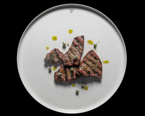 Gebratene Leberstücke mit Kräutern und Olivenöl auf einem weißen Teller. Ein einfaches, aber köstliches Leber Rezept.