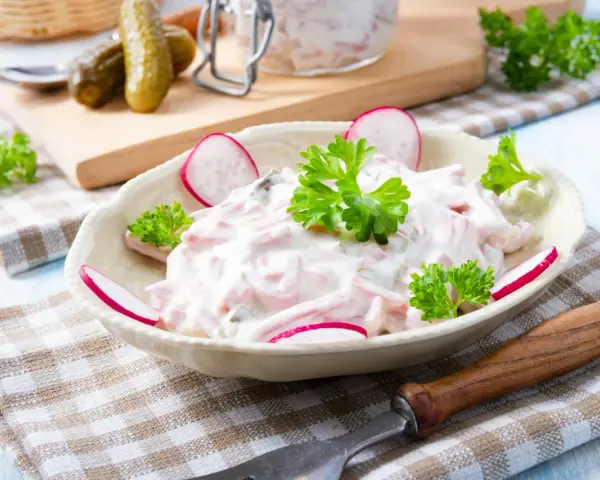 Ein cremiger Fleischsalat, garniert mit Radieschen und Petersilie. Ein einfaches und leckeres rezept fleischsalat für jede Gelegenheit.