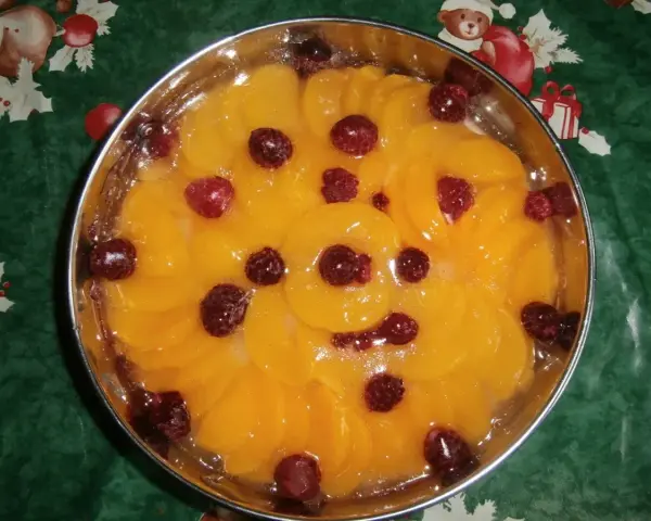 Fruchtiger Tortenboden ohne Ei, belegt mit Pfirsichspalten und Himbeeren in Gelee.