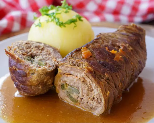 Herzhaftes Rouladen Rezept: Zarte Rinderrouladen mit Kartoffelklößen in einer kräftigen Soße, garniert mit Petersilie.