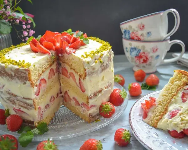 Erdbeerboden wie bei Oma: saftiger Biskuit mit viel frischen Erdbeeren und Sahne, verziert mit Pistazien. Ein Stück Kuchen zum Genießen.
