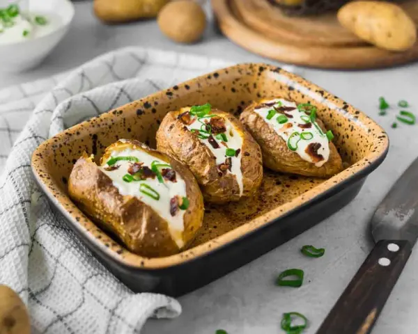 Drei gebackene Ofenkartoffeln mit Sour Cream und Speckwürfeln, ein köstliches Ofenkartoffeln Rezept.