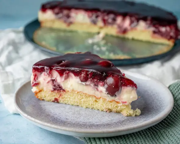 Ein saftiges Stück Kirsch-Sahne-Torte auf einem Teller, perfekt für ein schnelles obstkuchen rezept in der springform.