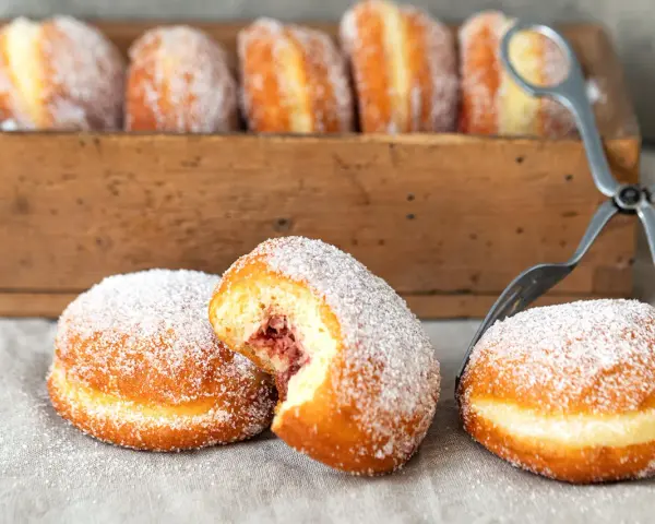 Zuckerüberzogene Berliner, eines davon mit Marmeladenfüllung, warten auf das nächste berliner rezept.