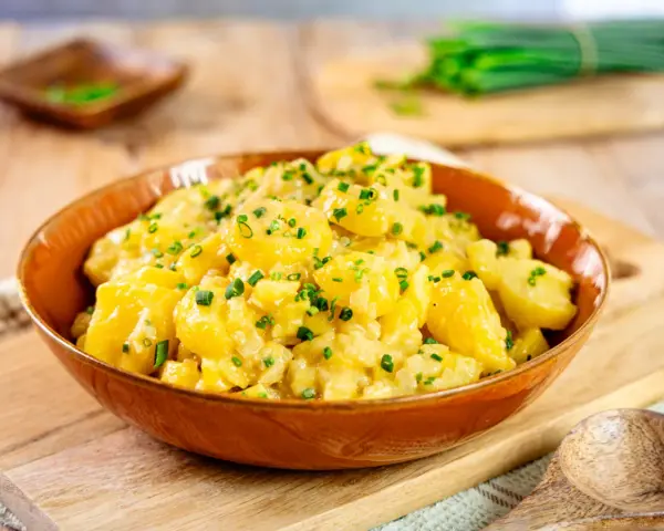 Ein köstlicher Kartoffelsalat, perfekt für jedes Kartoffelsalat Rezept. Mit frischen Kräutern garniert, bereit zum Servieren.