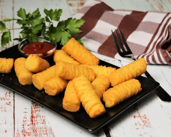 Goldbraune Kroketten, frisch zubereitet, liegen auf einem schwarzen Teller. Dazu gibt es Ketchup und frische Petersilie. Perfekt, um Kroketten selber machen zu lernen!