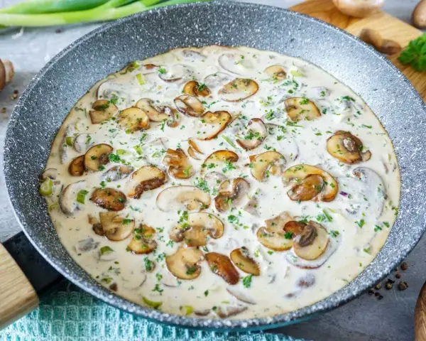Cremige Rahmchampignons in einer Pfanne, perfekt für ein schnelles und leckeres Rahmchampignons Rezept. Mit frischer Petersilie garniert.