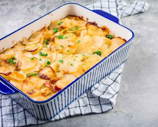 Ein goldbrauner Kartoffelauflauf, garniert mit Petersilie, bereit zum Servieren. Ein köstliches Kartoffelauflauf Rezept.