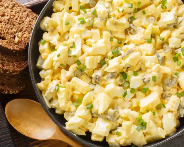 Cremiger Eiersalat mit Gurkenstückchen und Schnittlauch, perfekt für ein einfaches eiersalat rezept. Dazu passen rustikale Brotscheiben.