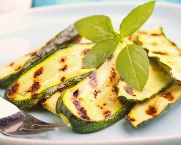 Gegrillte Zucchinischeiben mit Grillstreifen, garniert mit frischem Basilikum. Perfekt für die Sommerküche, diese Zucchini grillen marinade ist ein Genuss.