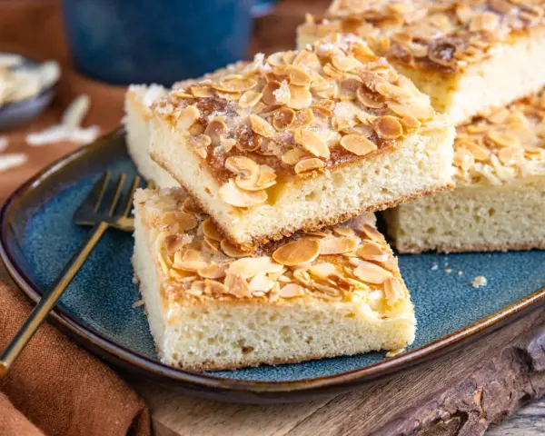 Original norddeutscher Butterkuchen mit Mandeln und Zucker bestreut, auf einem blauen Teller angerichtet.