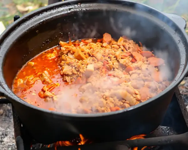 Ein dampfender Kessel mit herzhaftem Kesselgulasch, zubereitet über offenem Feuer. Das perfekte Rezept für ein rustikales Outdoor-Erlebnis.