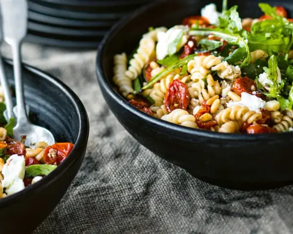 Leckerer Nudelsalat mit getrockneten Tomaten, Pinienkernen und Rucola. Ein einfaches nudelsalat rezept für den Sommer.