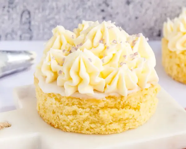 Ein kleiner Kuchen mit omas buttercreme ohne pudding, verziert mit lila Zuckerstreuseln.