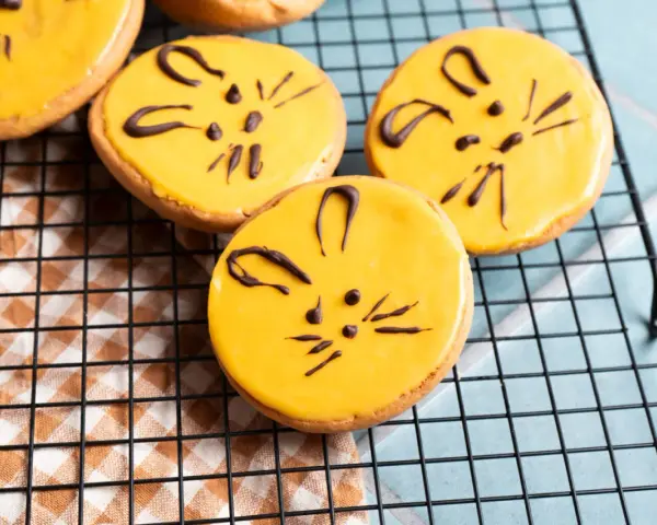 Süße Kekse mit gelber Glasur und Schokoladen-Katzenmotiven, ein tolles amerikaner rezept für Kinder.