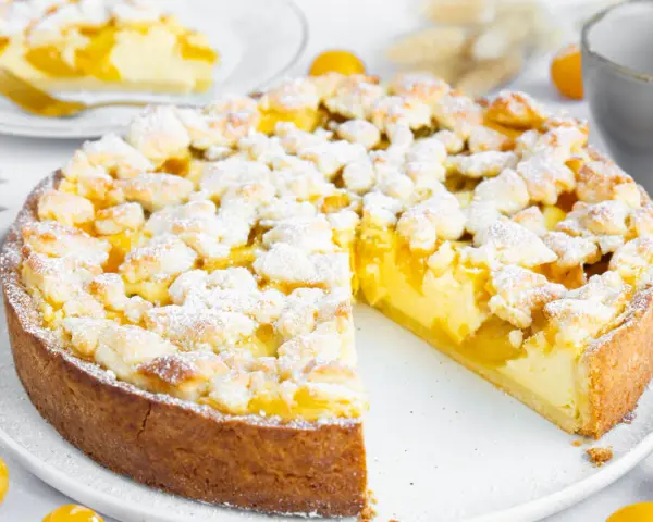 Ein saftiger Mirabellenkuchen mit Streuseln, wie ihn Landfrauen backen. Ein Stück ist bereits angeschnitten.