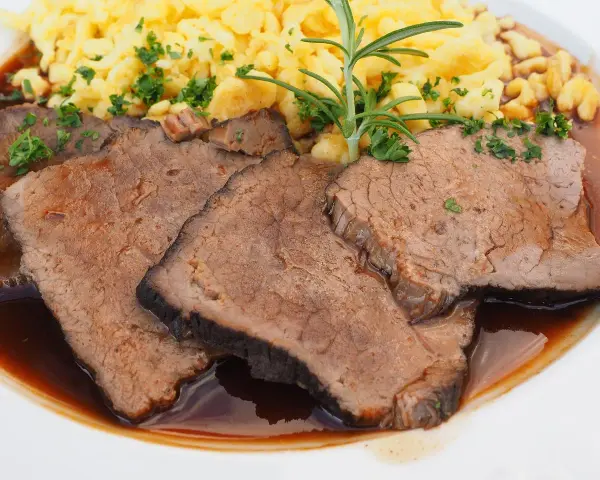 Saftige Scheiben Sauerbraten mit Spätzle und einer Kräutergarnitur. Ein klassisches Sauerbraten Rezept, das Appetit macht.